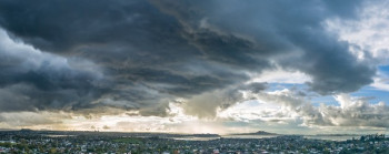 Dark grey clouds above a wide landscape of houses and trees.