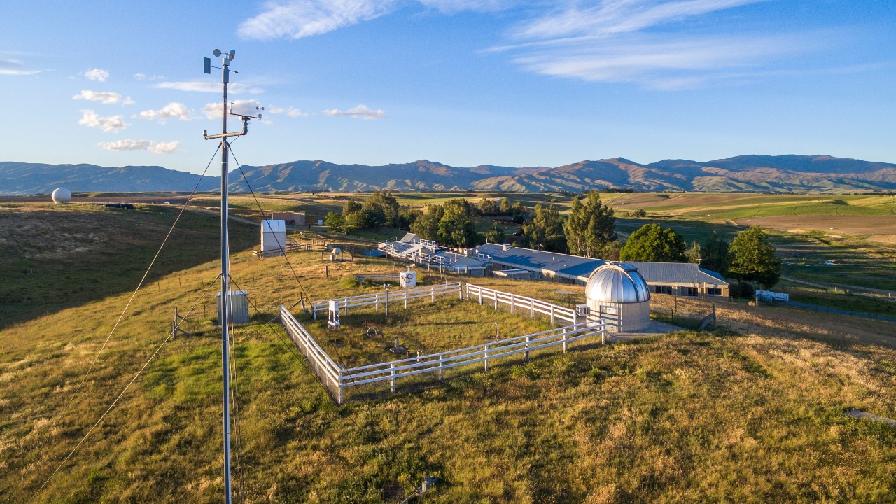 Weather-monitoring instruments in an open landscape with blue sky behind.