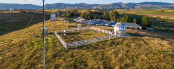 Weather-monitoring instruments in an open landscape with blue sky behind.