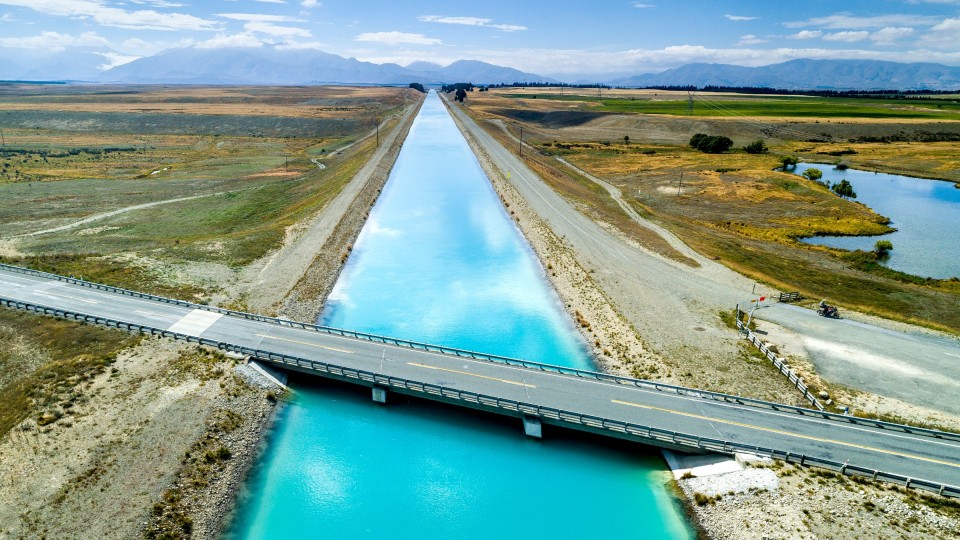 A straight, man-made river with a road-bridge across it.